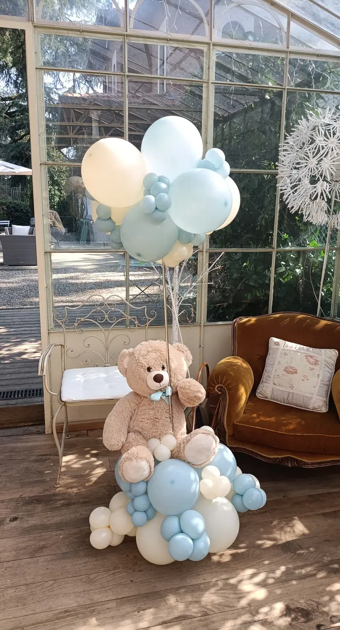 Composizione di palloncini azzurri e crema con orsetto, allestimento per battesimo